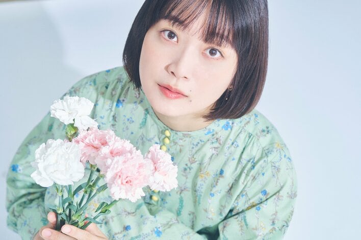 【写真】役柄を表現した花とともにキュートな表情を浮かべる深川麻衣の写真を見る